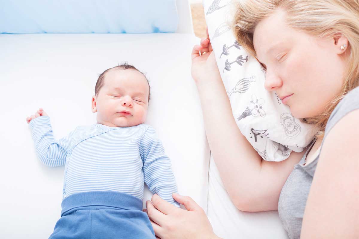 Une maman endormie avec son bébé dans un lit | Dr François Auger Chiropraticien - Chiropratique Québec, Chiro Nord, Stoneham, NDL, Lac Saint-Charles