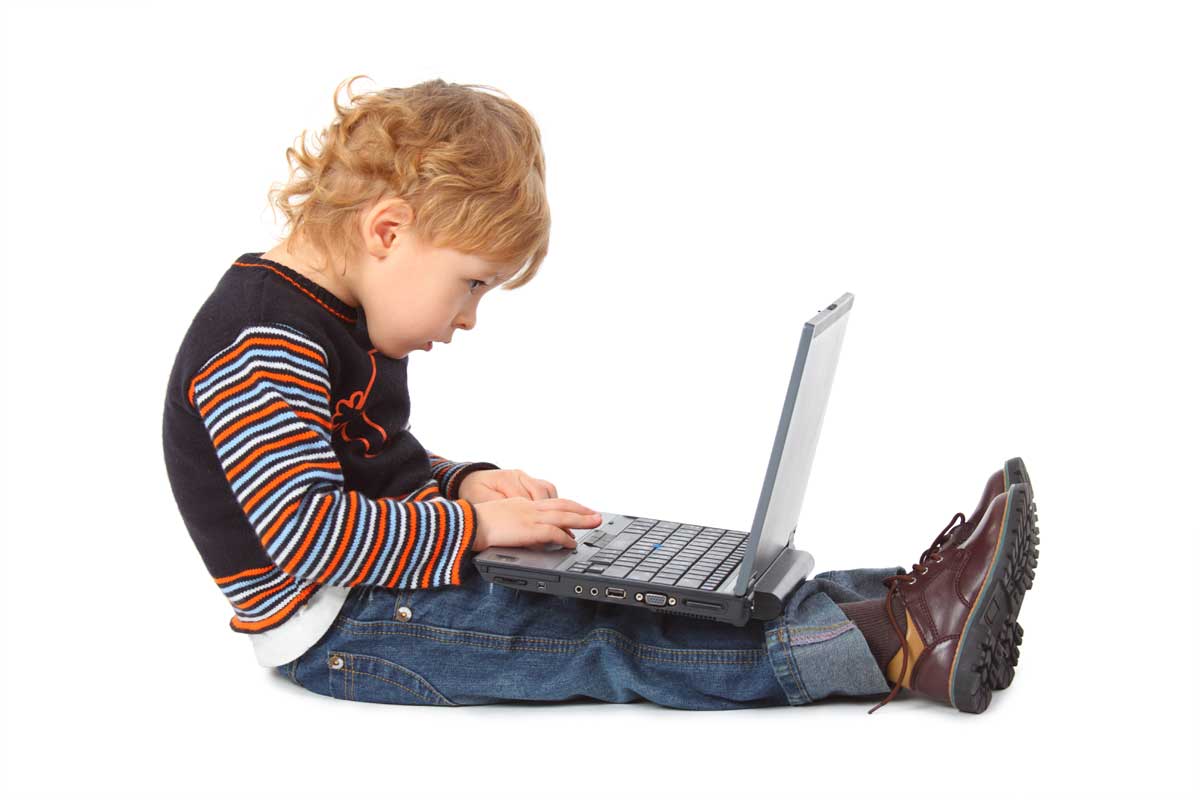 Un enfant assis par terre qui regarde un ordinateur. Sa tête est penchée et son dos est arrondi | Dr François Auger Chiropraticien - Chiropratique Québec, Chiro Nord, Stoneham, NDL, Lac Saint-Charles