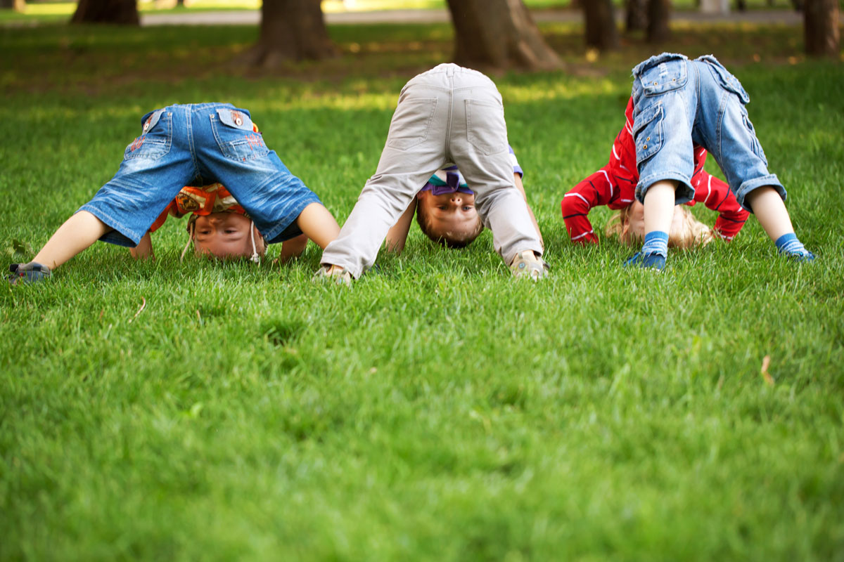 3 enfants qui s'amusent dans le gazon en faisant des roulades | Dr François Auger Chiropraticien - Chiropratique Québec, Chiro Nord, Stoneham, NDL, Lac Saint-Charles