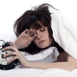 Une femme qui manque de sommeil ou qui a très mal dormi et qui tente d'arrêter son alarme du matin | Dr François Auger Chiropraticien - Chiropratique Québec, Chiro Nord, Stoneham, NDL, Lac Saint-Charles