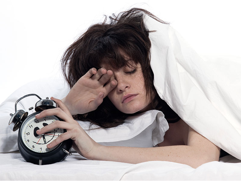 Une femme qui manque de sommeil ou qui a très mal dormi et qui tente d'arrêter son alarme du matin | Dr François Auger Chiropraticien - Chiropratique Québec, Chiro Nord, Stoneham, NDL, Lac Saint-Charles